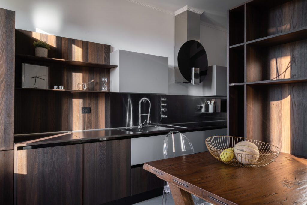 zona pranzo con tavolo in legno e cucina moderna progetto Crucitti Architetti